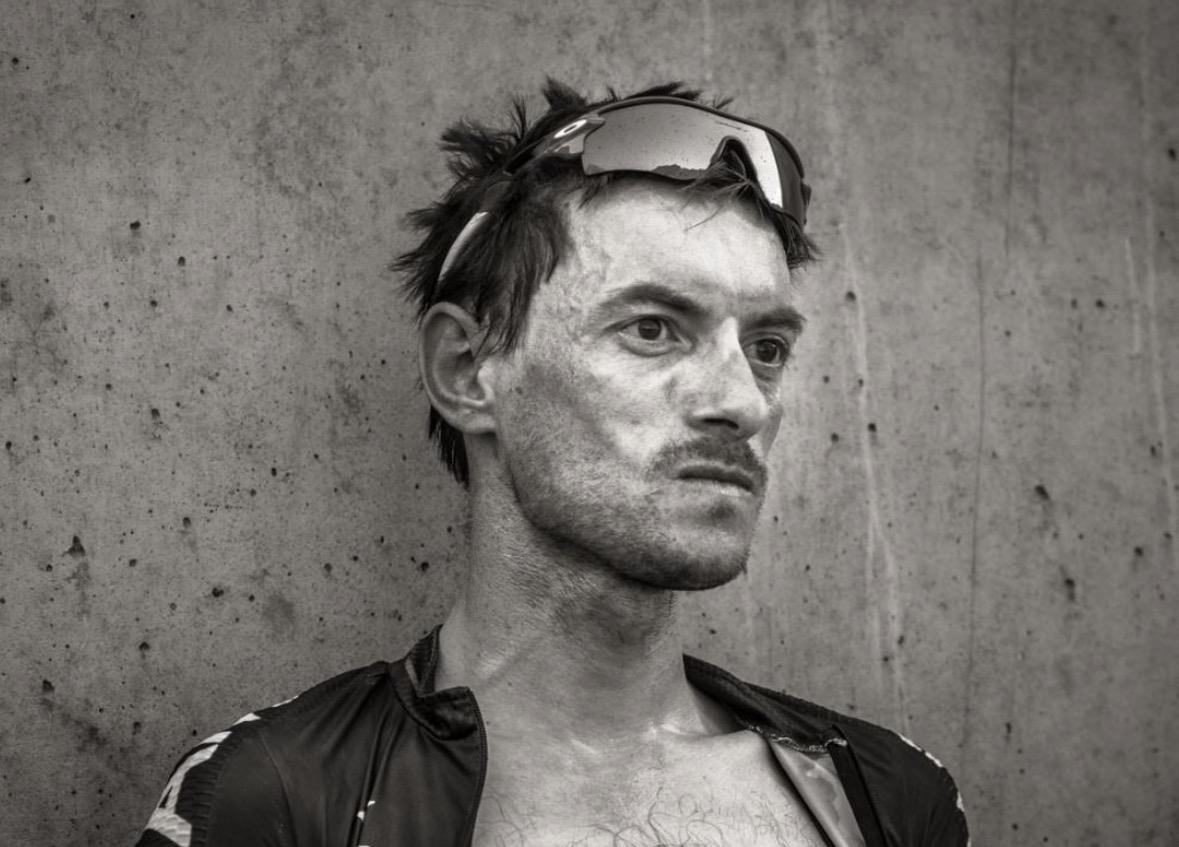 A rider photographed after a race, face covered in road dust